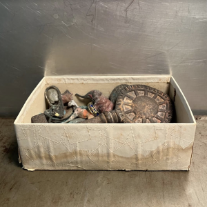 Photograph of a box with several metal and stone items in it.